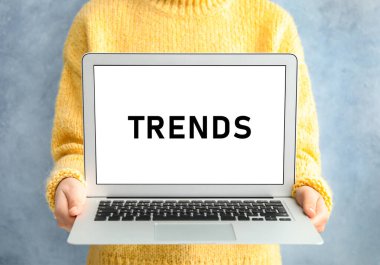 Yeni trendler. Dizüstü bilgisayarı açık mavi arka planda tutan kadın, yakın plan.