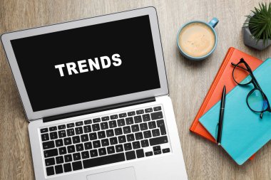 Yeni trendler. Modern dizüstü bilgisayar, bir fincan kahve ve ahşap masa üzerinde ofis kırtasiyesi.