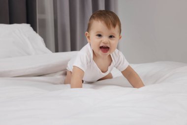 Evdeki yatakta oynayan komik küçük bebek