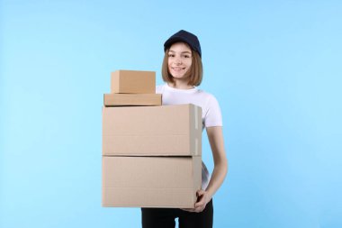 Happy postwoman with parcels on light blue background clipart