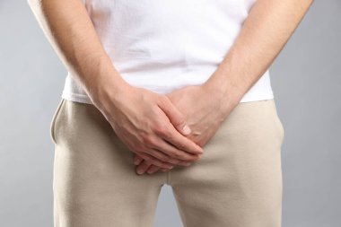 Cinsel yolla bulaşan hastalıklar. Gri arka planda semptomlardan muzdarip bir adam, yakın plan