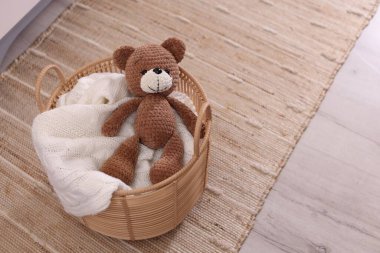 Battaniyeli hasır sepet ve içeride oyuncak ayı. Metin için boşluk