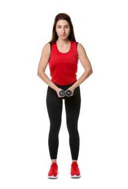 Spor kıyafetli bir kadın, beyaz arka planda halterlerle egzersiz yapıyor.