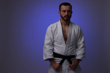 Koyu mor arka planda üniformalı bir karate dövüşçüsü. Metin için boşluk