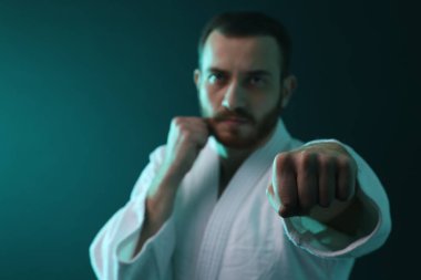 Üniformalı bir adam renkli ışıklarda karate çalışıyor, seçici odaklanma. Metin için boşluk