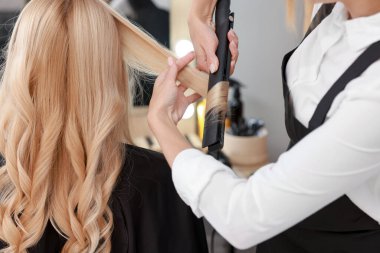 Kuaför kıvırcık saçlı kadın, kuaförde düz ütü, yakın plan.