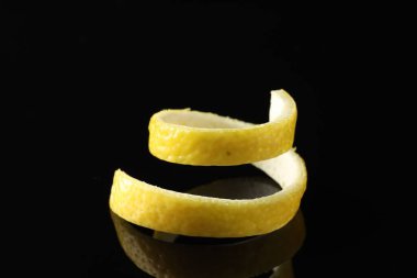 Siyah ayna yüzeyinde bir kıvırcık limon kabuğu, yakın plan.