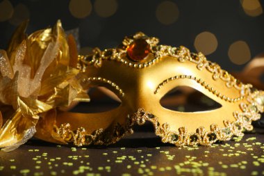 Güzel bir karnaval maskesi ve koyu arkaplanda bulanık ışıkları olan konfeti, yakın plan.