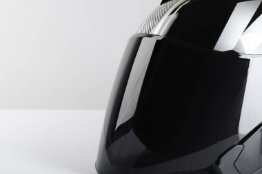 Işık arka planında güneşliği olan modern motosiklet kaskı, yakın plan. Metin için boşluk