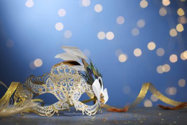 Masadaki güzel karnaval maskesi ve konfeti bulanık ışıklarla mavi arka planda.