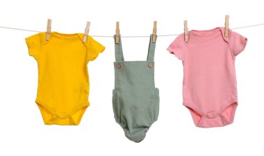 Different baby clothes drying on laundry line against white background