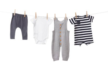 Different baby clothes drying on laundry line against white background