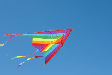 Mavi gökyüzünde uçan renkli bir uçurtma