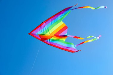 Mavi gökyüzünde uçan renkli bir uçurtma