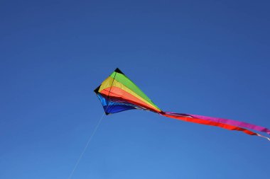 Mavi gökyüzünde uçan renkli bir uçurtma