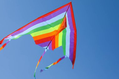 Mavi gökyüzünde uçan renkli bir uçurtma