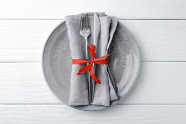Şık bir tabak, çatal bıçak ve peçete beyaz ahşap masa, üst manzara.