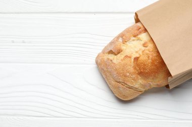 Beyaz ahşap masa üzerinde taze baget ve kağıt torba, üst manzara. Metin için boşluk