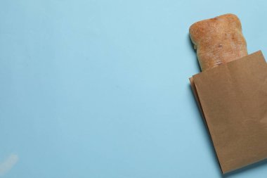 Açık mavi arka planda taze ciabatta ile kağıt torba, üst manzara. Metin için boşluk