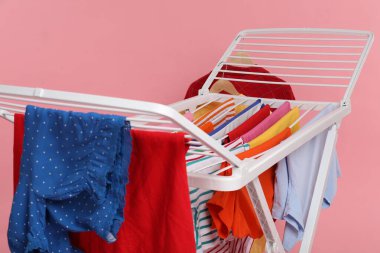 Açık pembe arka planda temiz çamaşırları olan kuru askı, yakın plan.