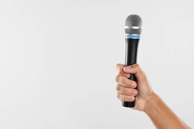 Açık gri arka planda mikrofonu olan adam, yakın plan. Metin için boşluk