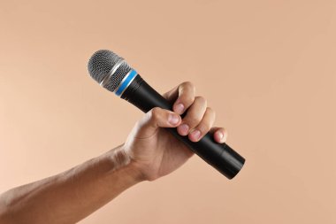 Bej arka planda mikrofonu olan adam, yakın plan.