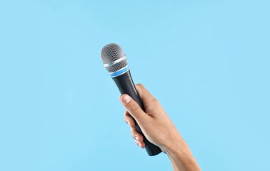 Açık mavi arka planda mikrofonu olan adam, yakın plan.