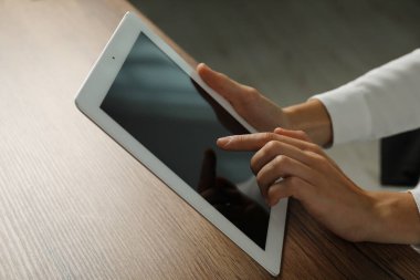 İş kadını, kapalı bir masada tablet kullanıyor, yakın plan. Modern teknoloji