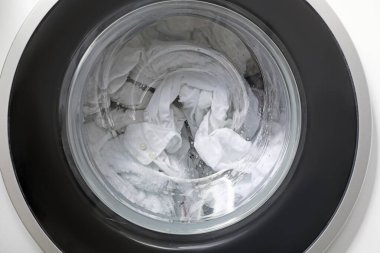 Arka planda giysileri olan çamaşır makinesi, yakın plan