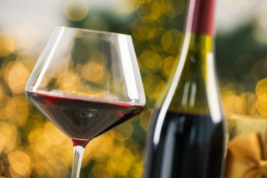 Bulanık Noel ışıklarına karşı bir şişe kırmızı şarap, yakın plan. Bokeh etkisi