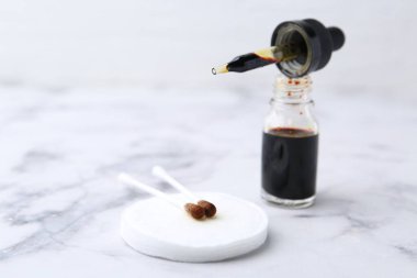 Bir şişe sulu iyot, pipetli ve beyaz mermer masa üzerinde pamuklu çubuklar, yakın plan. Metin için boşluk