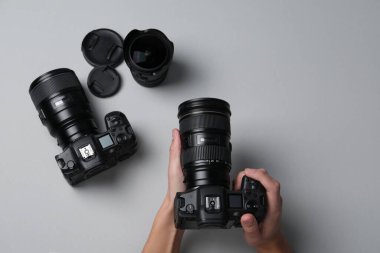 Gri arka planda profesyonel kamerası olan fotoğrafçı, üst görünüm