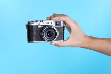 Açık mavi arkaplanda klasik kameralı fotoğrafçı, yakın plan