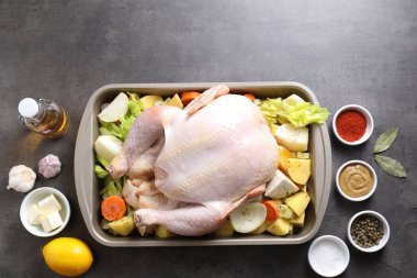 Çiğ hindi, farklı sebzeler ve baharatlarla gri masada, düz yerde. Metin için boşluk