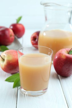 Beyaz ahşap masada elma suyu ve meyveler tazeleniyor.