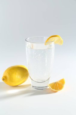 Açık gri zemin üzerinde limon ve bardakta soda tazeleniyor.
