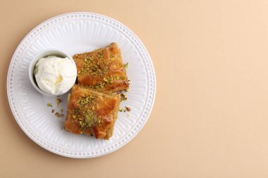 Ezilmiş fındıklı enfes baklava ve bej masa üzerinde dondurma, üst manzara. Metin için boşluk