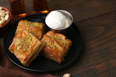 Ahşap masada servis edilen ezilmiş fındıklı ve dondurmalı enfes baklava, yakın plan. Metin için boşluk