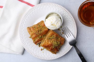 Gri masada servis edilen ezilmiş fındıklı ve dondurmalı enfes baklavalar.