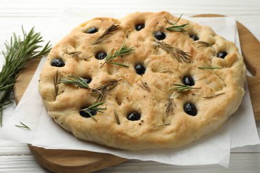 Zeytinli ve biberiyeli lezzetli Focaccia ekmeği beyaz ahşap masada, yakın plan.