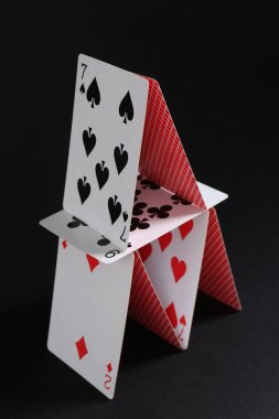 House of playing cards on black background clipart