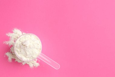 Protein tozu ve pembe arka planda kepçe, üst manzara. Metin için boşluk