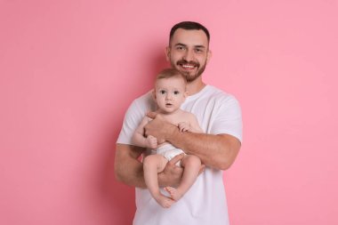 Pembe arka planda sevimli bebeği olan baba.