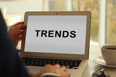 Yeni trendler. İçerideki masada dizüstü bilgisayar kullanan adam, yakın plan.