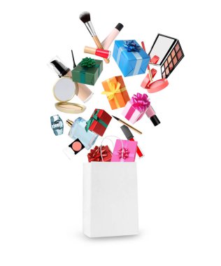 Farklı makyaj ürünleri beyaz arka planda kağıt alışveriş çantasına düşüyor. Dekoratif kozmetik