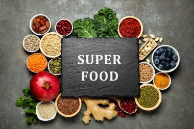 Süper yemek. Farklı sağlıklı gıda ürünleri ve gri masada boş bir tahta.