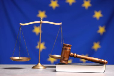Adalet terazisi, hakimin tokmağı ve kitabı Avrupa Birliği bayrağına karşı masada