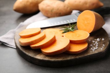 Taze çiğ patates, baharat ve bıçak gri masada, yakın plan.