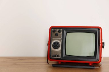 Beyaz duvara karşı ahşap rafta duran eski televizyon seti. Metin için boşluk