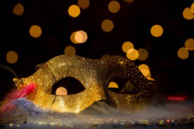Güzel bir karnaval maskesi ve karanlık arka planda duman içinde konfeti, bulanık ışıklar, yakın çekim